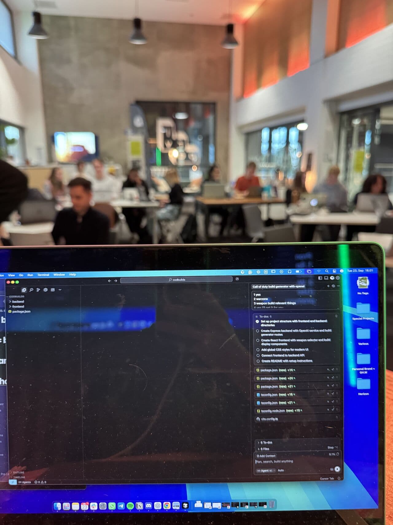 A laptop with code open at a Femcode coding session, people working at tables behind it